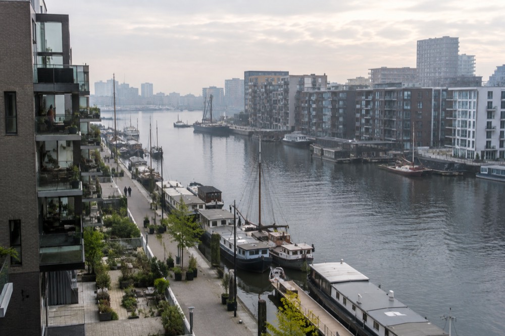 Modern apartment buildings along a docklands quay with moored boats and open water