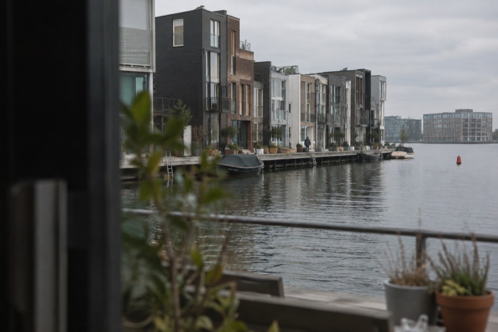 Row of narrow modern houses on a narrow peninsula jutting into harbour water