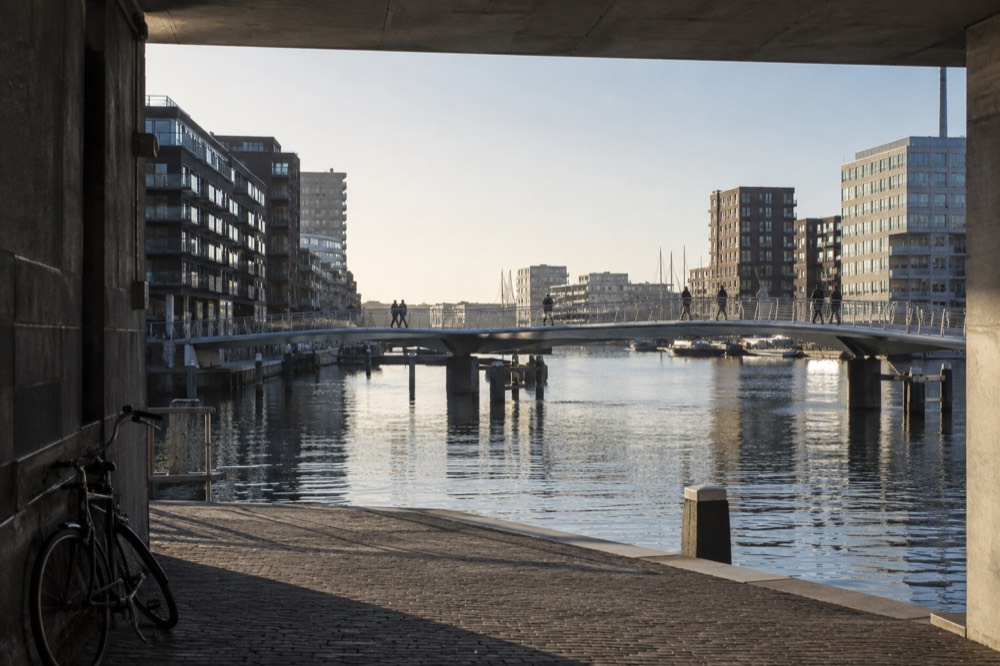 Pedestrian bridge over open harbour water with modern housing on both banks