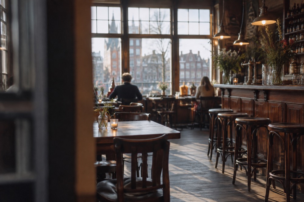 A traditional Amsterdam café interior with wooden tables and a long bar