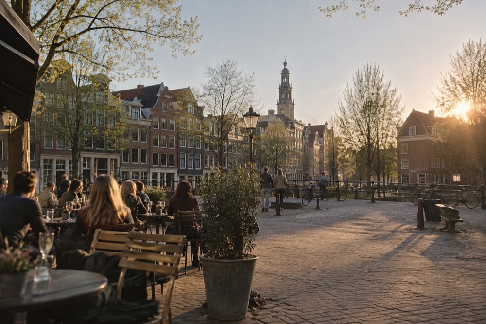 Café terrace tables beside a small square with old brick buildings in the Jordaan