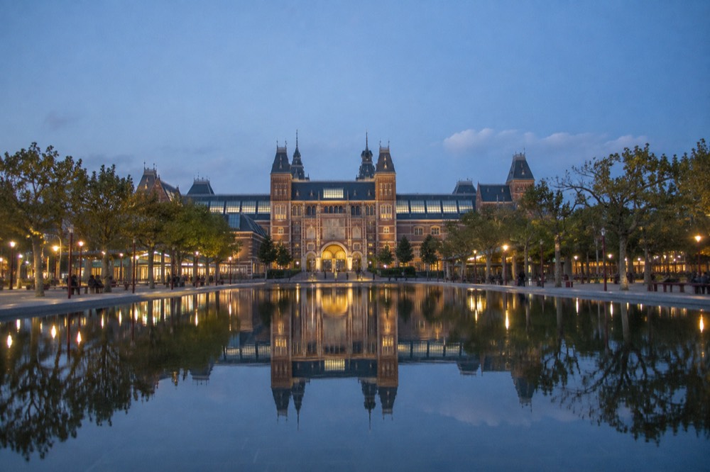 The large pond in front of the Rijksmuseum building reflected in still water on a clear day