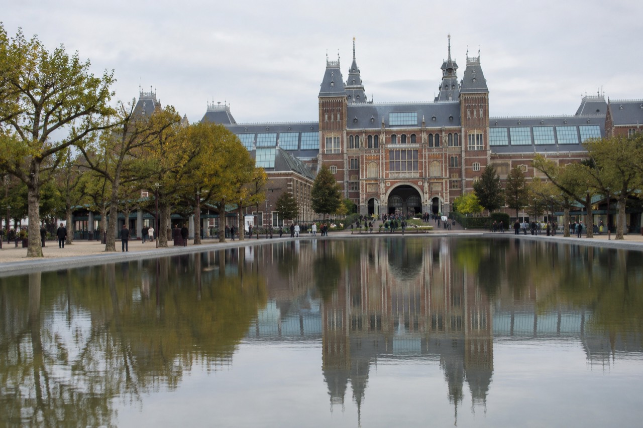 The large pond in front of the Rijksmuseum building reflected in still water on a clear day