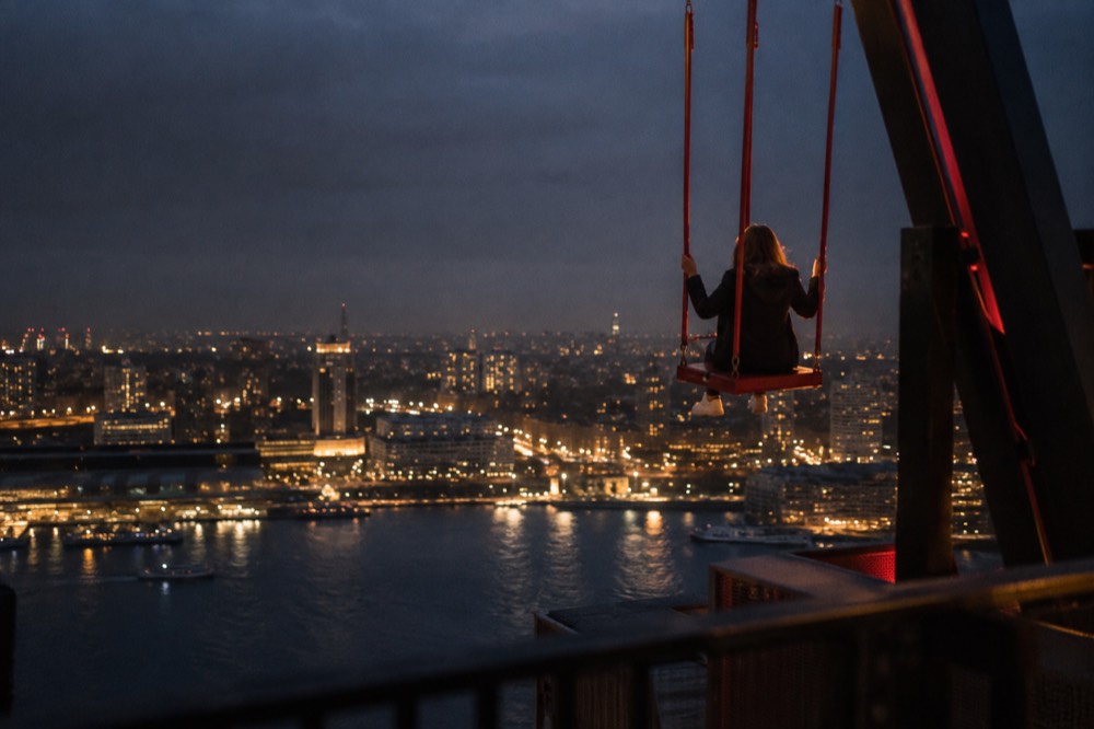 Person on the Over the Edge swing with Amsterdam cityscape visible below