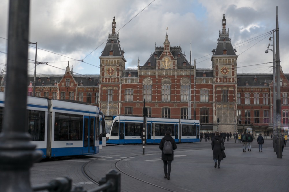 The brick facade of Amsterdam Centraal Station seen from the station square with trams in the foreground