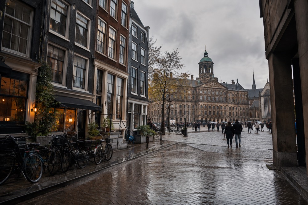 Narrow historic canal houses along a busy Amsterdam street with bicycles parked outside