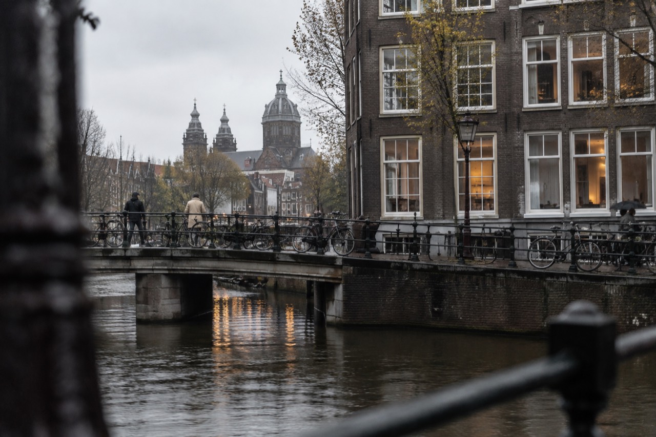 A canal-side Amsterdam building with bicycles parked along the railing