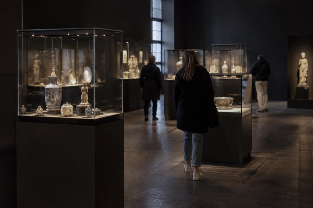 A quiet museum gallery with spotlit display cases and dark walls