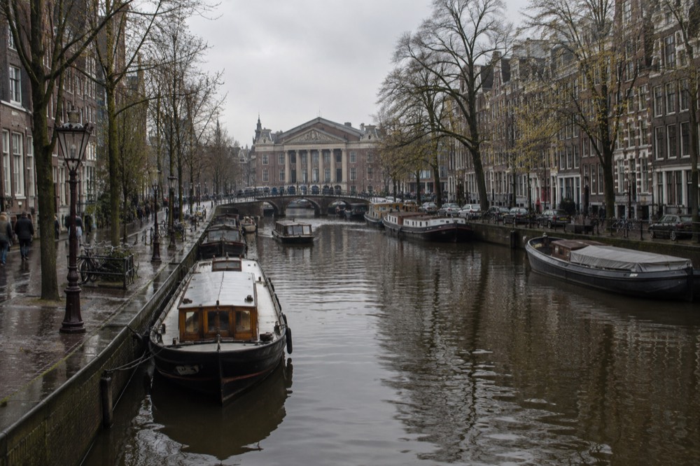View along the Amstel river from the Blauwbrug bridge toward a classical museum facade