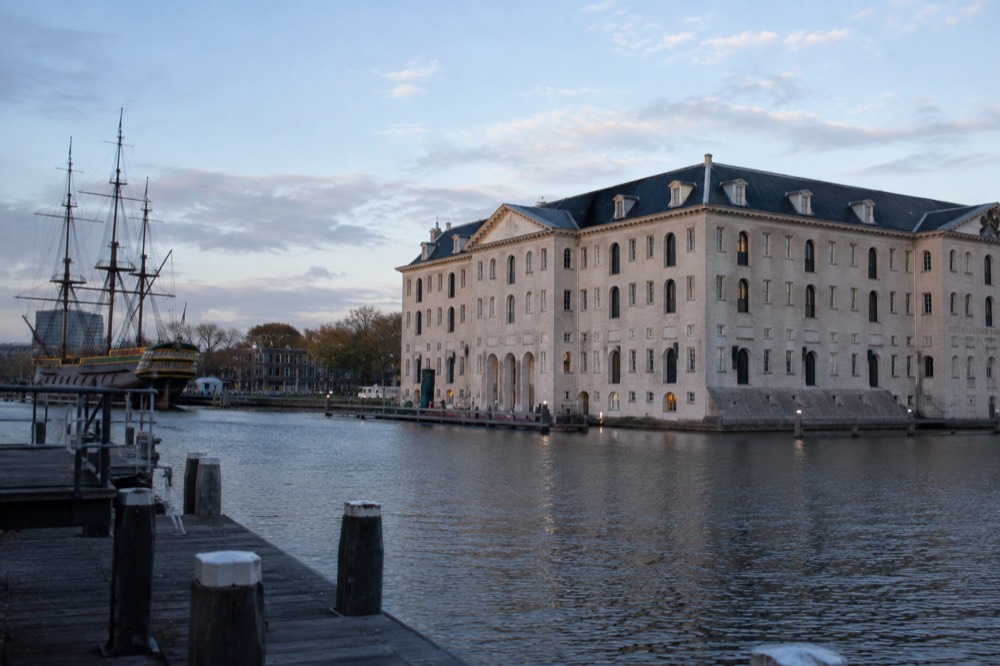 The stone facade of the National Maritime Museum above the Oosterdok water on a bright day