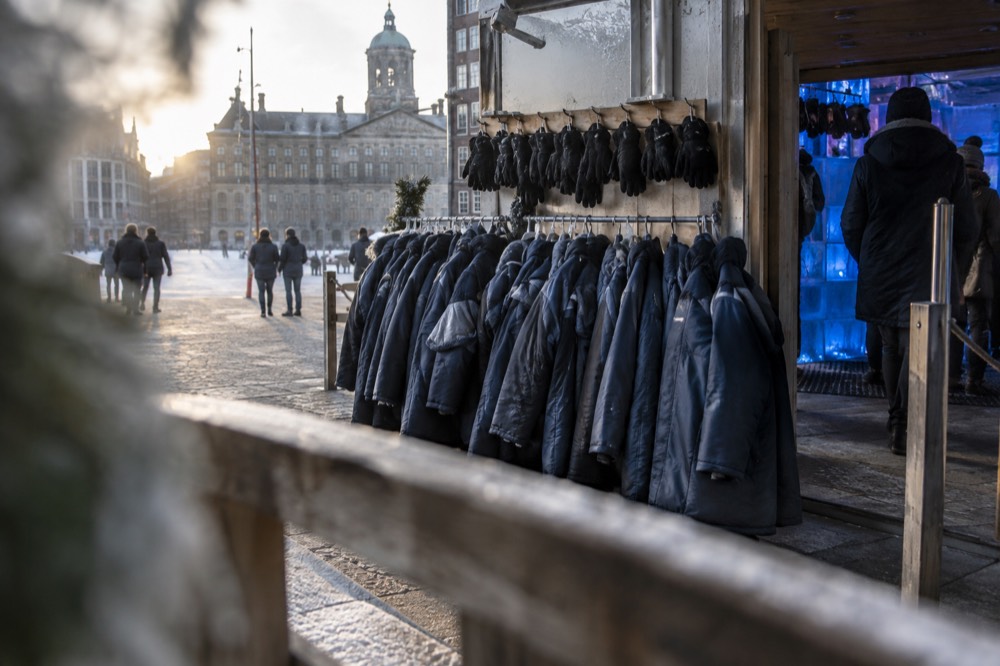 Rows of insulated thermal coats and gloves hanging on hooks ready for guests entering a frozen bar