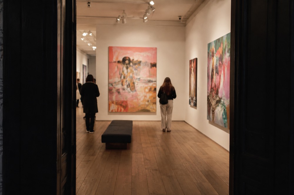 Bright gallery room with large colourful canvases and spotlit paintings on white walls