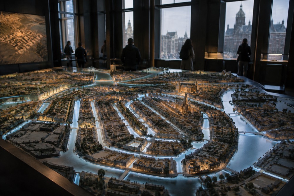 A scale model of Amsterdam's canal ring lit with projections inside a dim museum room