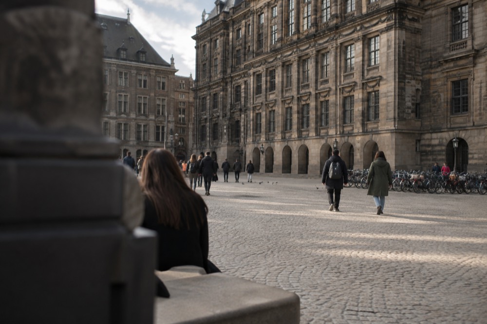 A quiet paved square with a large museum building and rows of bicycles parked along its edge