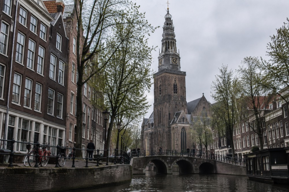 Gothic brick church tower rising above old Amsterdam canal houses
