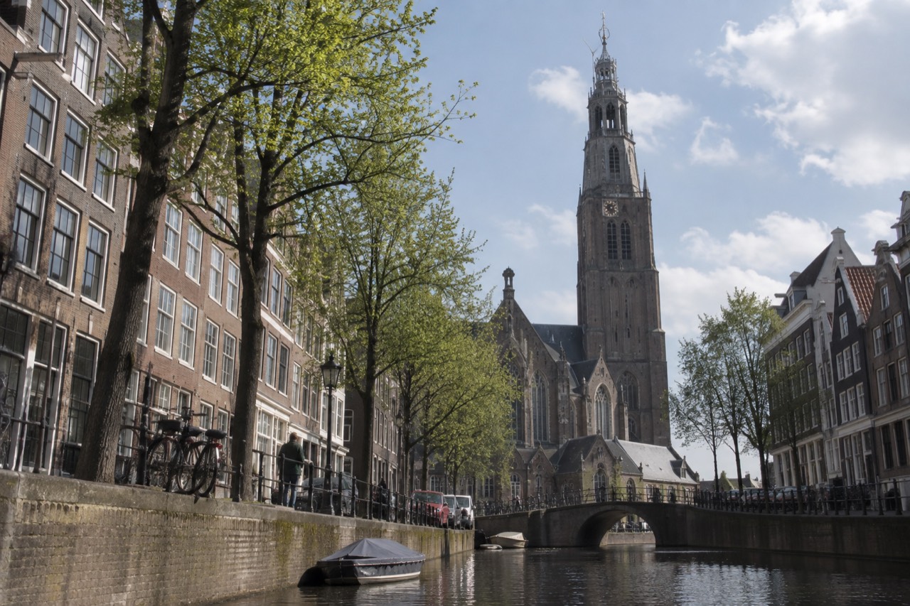 Gothic brick church tower rising above old Amsterdam canal houses