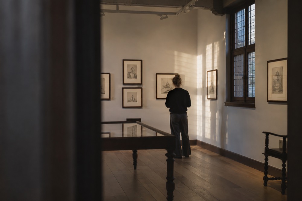 A quiet museum gallery with drawings displayed on pale walls under soft lighting