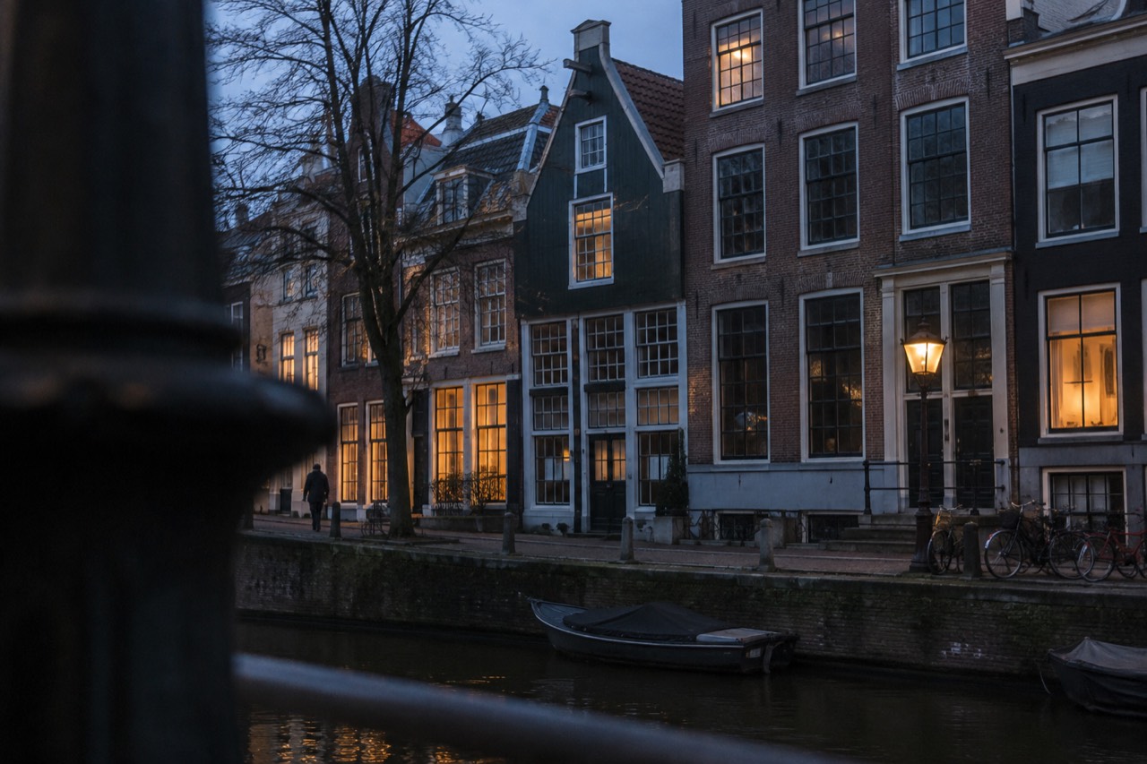 A narrow 17th-century Amsterdam canal house with a green wooden facade and tall windows