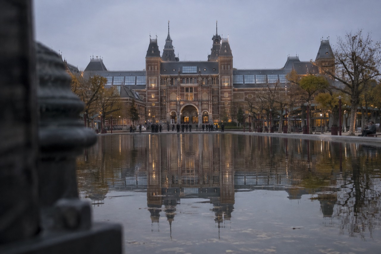 The Rijksmuseum building reflected in the water of the Museumplein pond at dusk