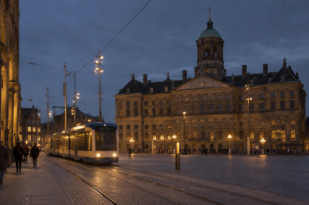 Tram on a city street beside a large square and classical building