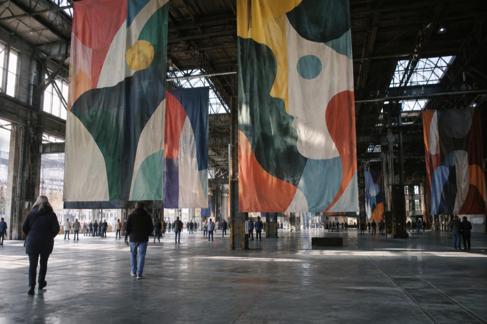 Oversized colourful murals hung from the ceiling beams of a wide industrial warehouse