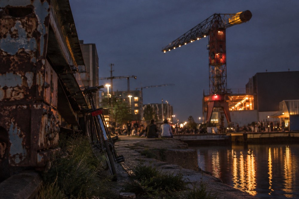 People walking past NDSM Wharf, seen from across the street