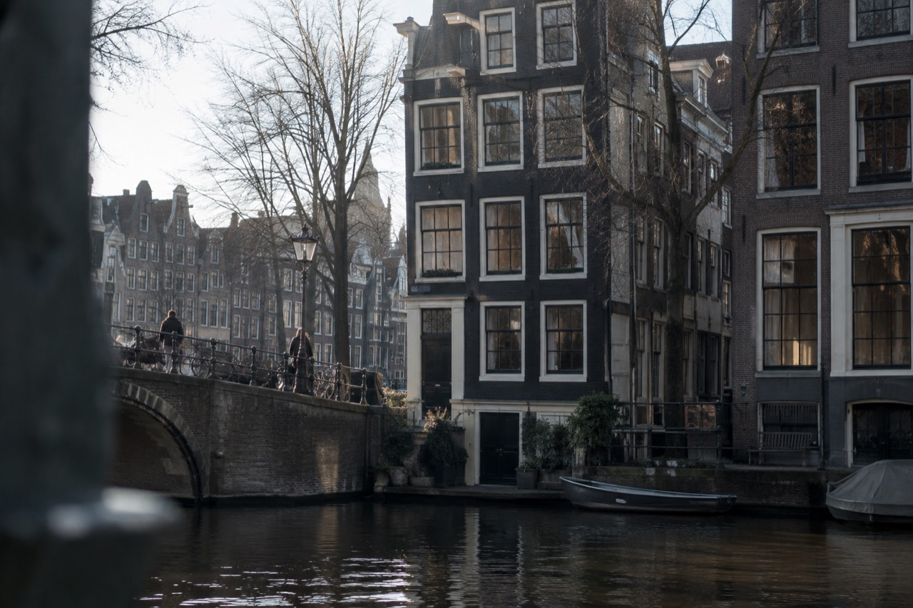A narrow medieval canal house facade on the Singel in Amsterdam beside dark water