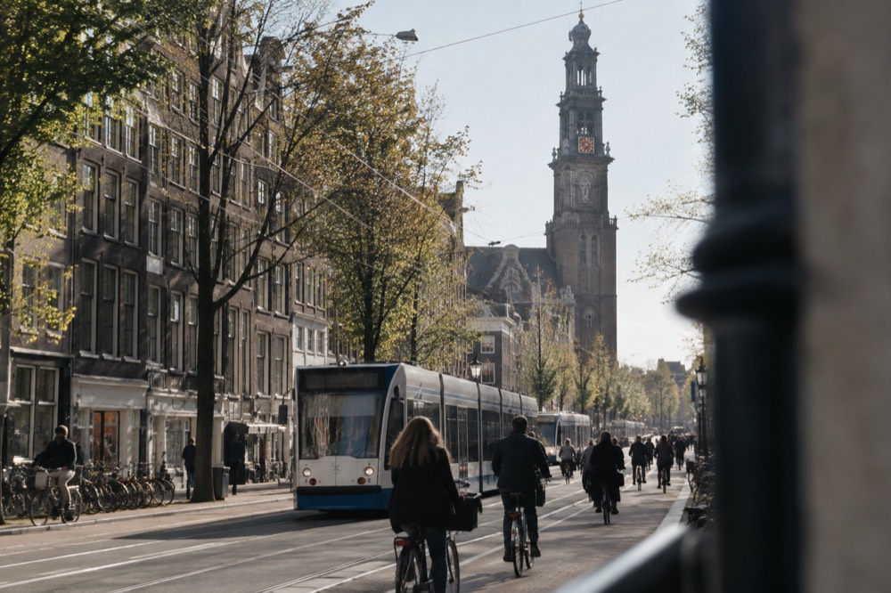 Trams and cyclists passing along the Raadhuisstraat toward the Westerkerk tower