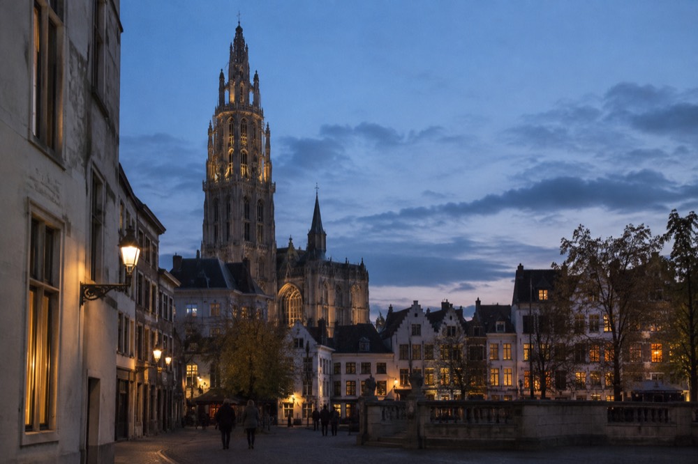 A large gothic cathedral tower rising above narrow streets and old houses