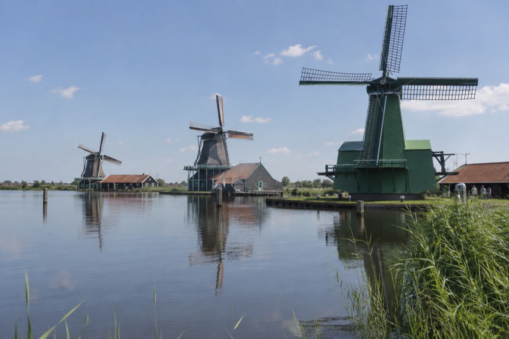 Row of historic windmills reflected in still water at Zaanse Schans