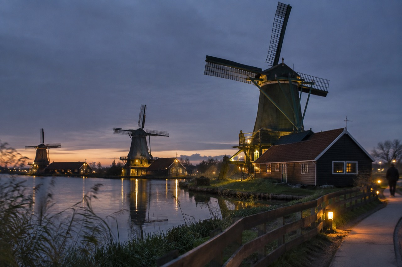 Historic Dutch windmills standing along a green waterway at Zaanse Schans