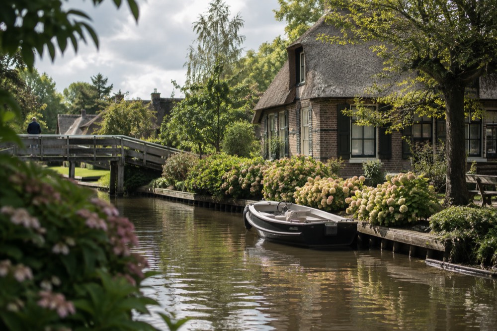 A small electric boat moored beside a thatched cottage on a Giethoorn canal