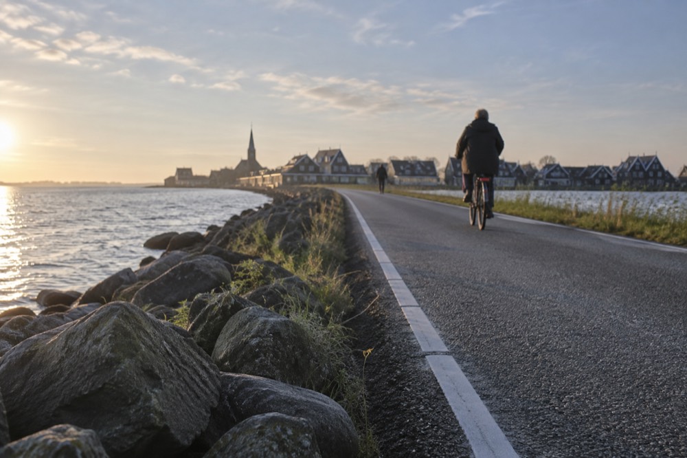 A causeway road crossing open water toward a village of dark timber houses