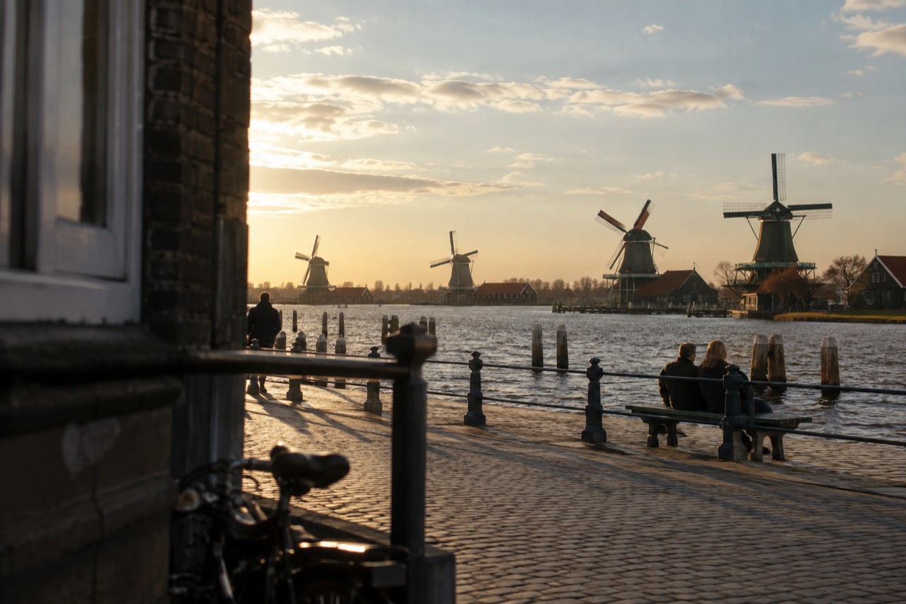 A row of historic Dutch windmills standing beside a waterfront under a wide sky