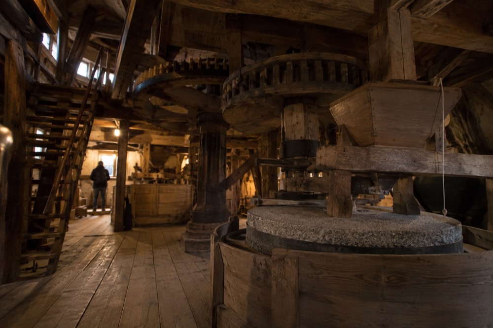 Interior of a historic Dutch windmill showing wooden gears and millstones in low light