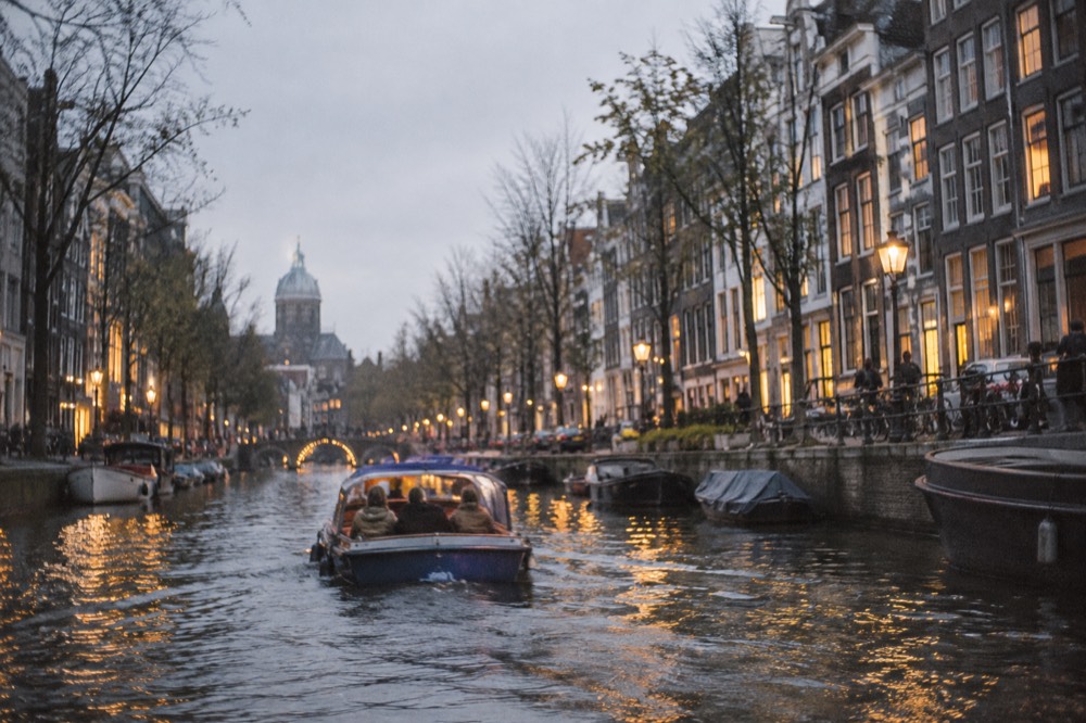 A small saloon boat passing lit canal houses on an evening Amsterdam cruise