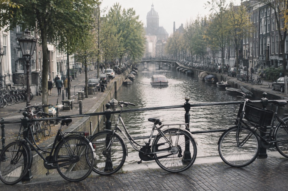 A canal-side street in the Amsterdam city centre with bicycles parked against a bridge railing.