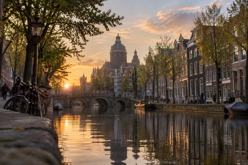 A quiet canal in Amsterdam at dusk with narrow houses reflected in the water