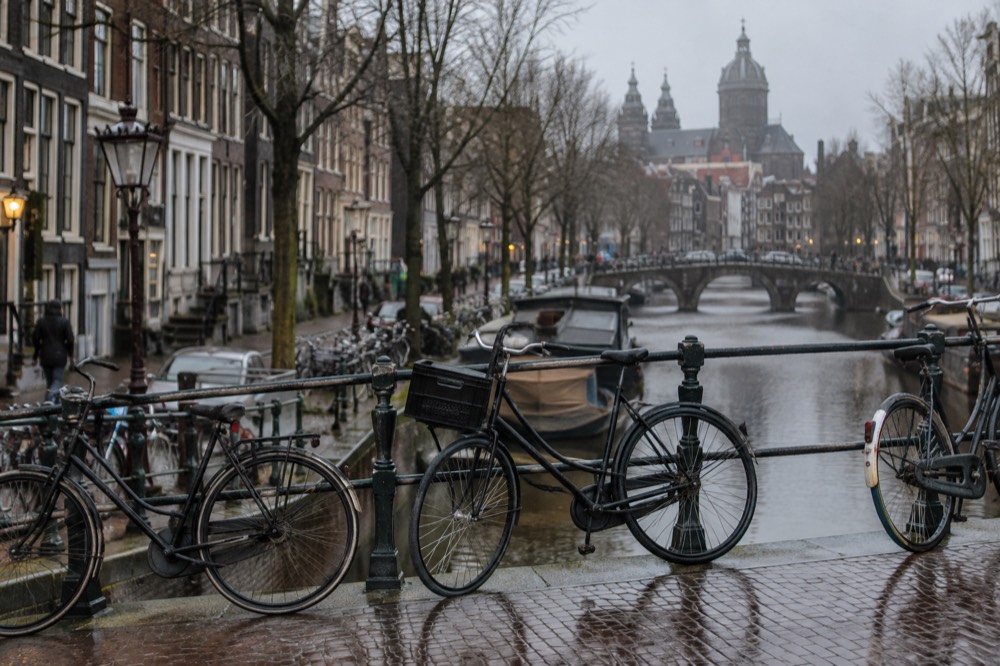 Bicycles parked on a bridge over an Amsterdam canal in soft morning light