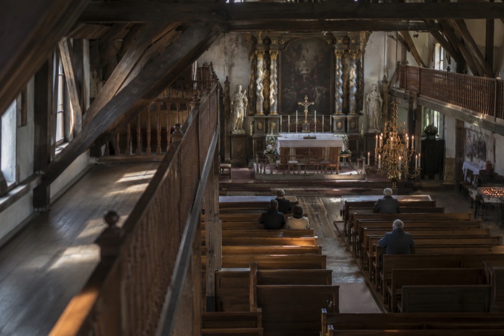 Inside a hidden attic church with a baroque altar and wooden pews