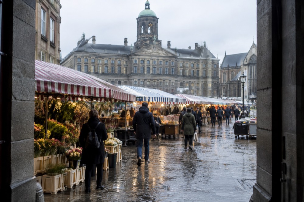 Rows of market stalls with striped awnings along a busy Amsterdam street