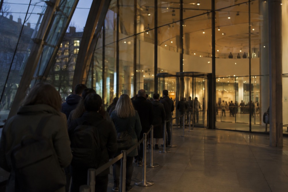 The glass entrance hall of the Van Gogh Museum with visitors queueing in an ordered line