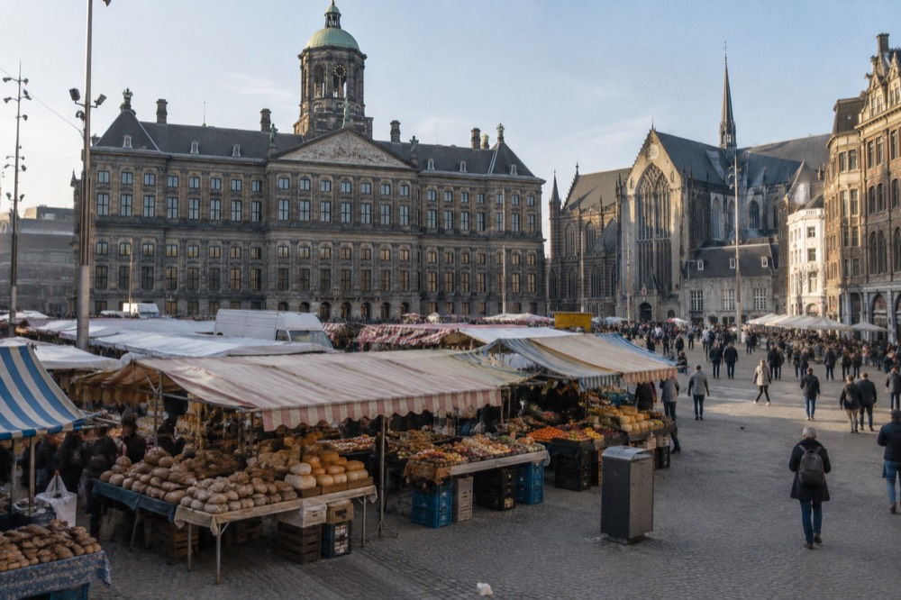 A market stall piled with fresh bread, cheese and fruit under striped awnings