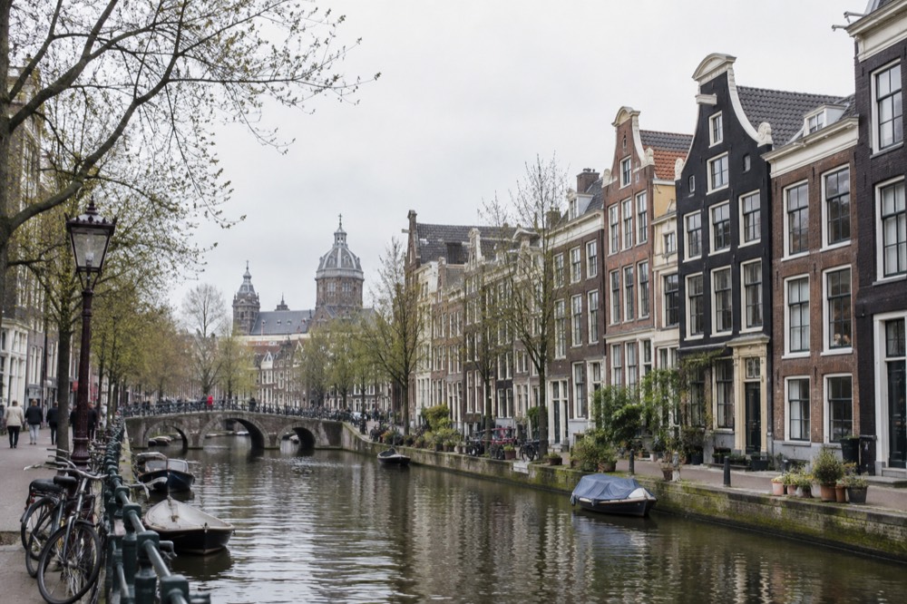 Row of narrow canal houses with hooked gables along an Amsterdam gracht