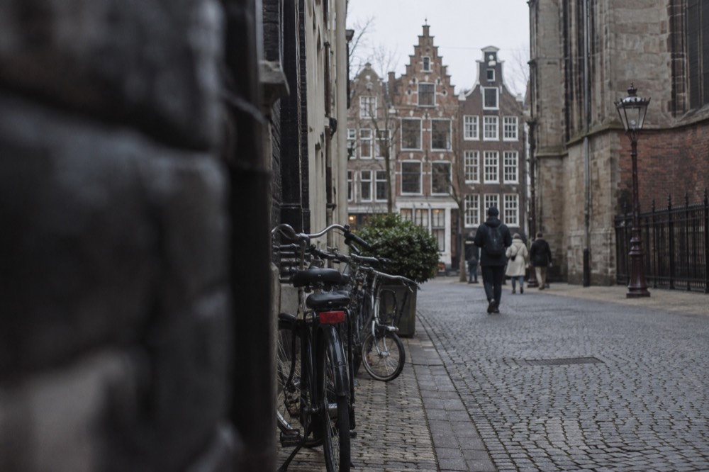 A narrow cobbled street lined with step-gabled houses and bicycles parked against a wall