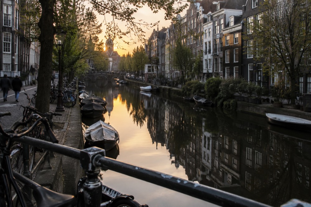 Canal houses reflected in still water along a narrow Amsterdam gracht at dusk