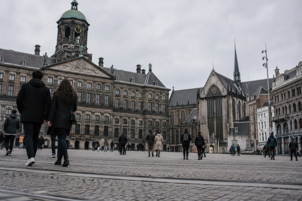 People walking past Dam Square, seen from across the street