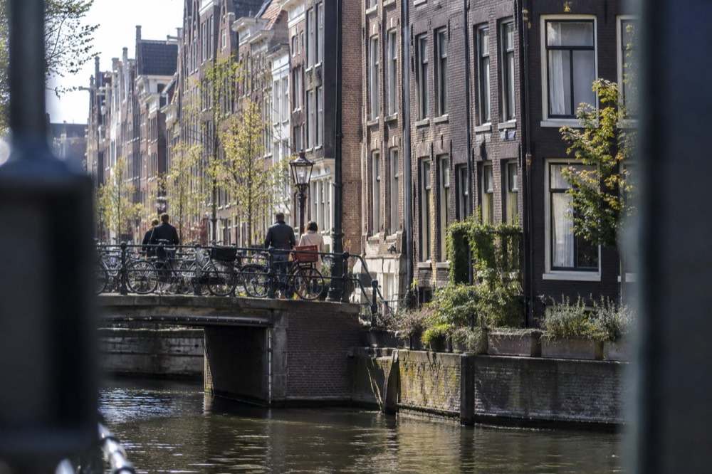 Narrow Amsterdam street with brick facades and bicycles parked along a canal railing