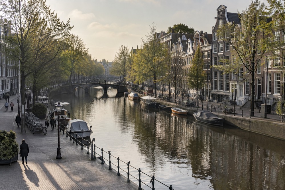 Gabled canal houses lining an Amsterdam gracht with trees along the water