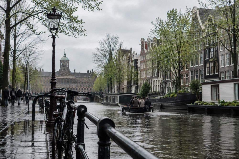 Amsterdam canal in spring with trees in leaf and a small boat passing gabled houses